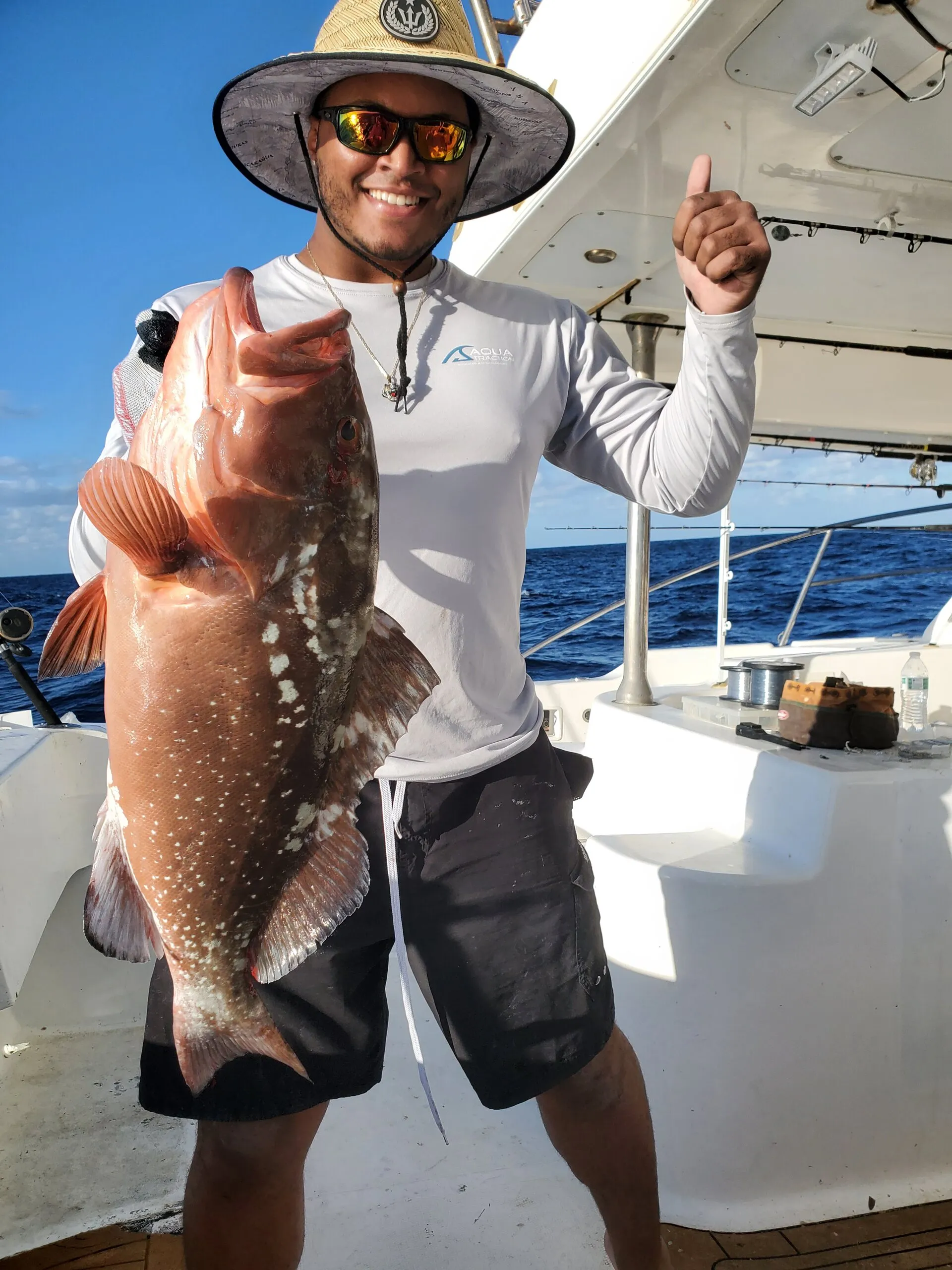 Angler in a sun hat with a red grouper