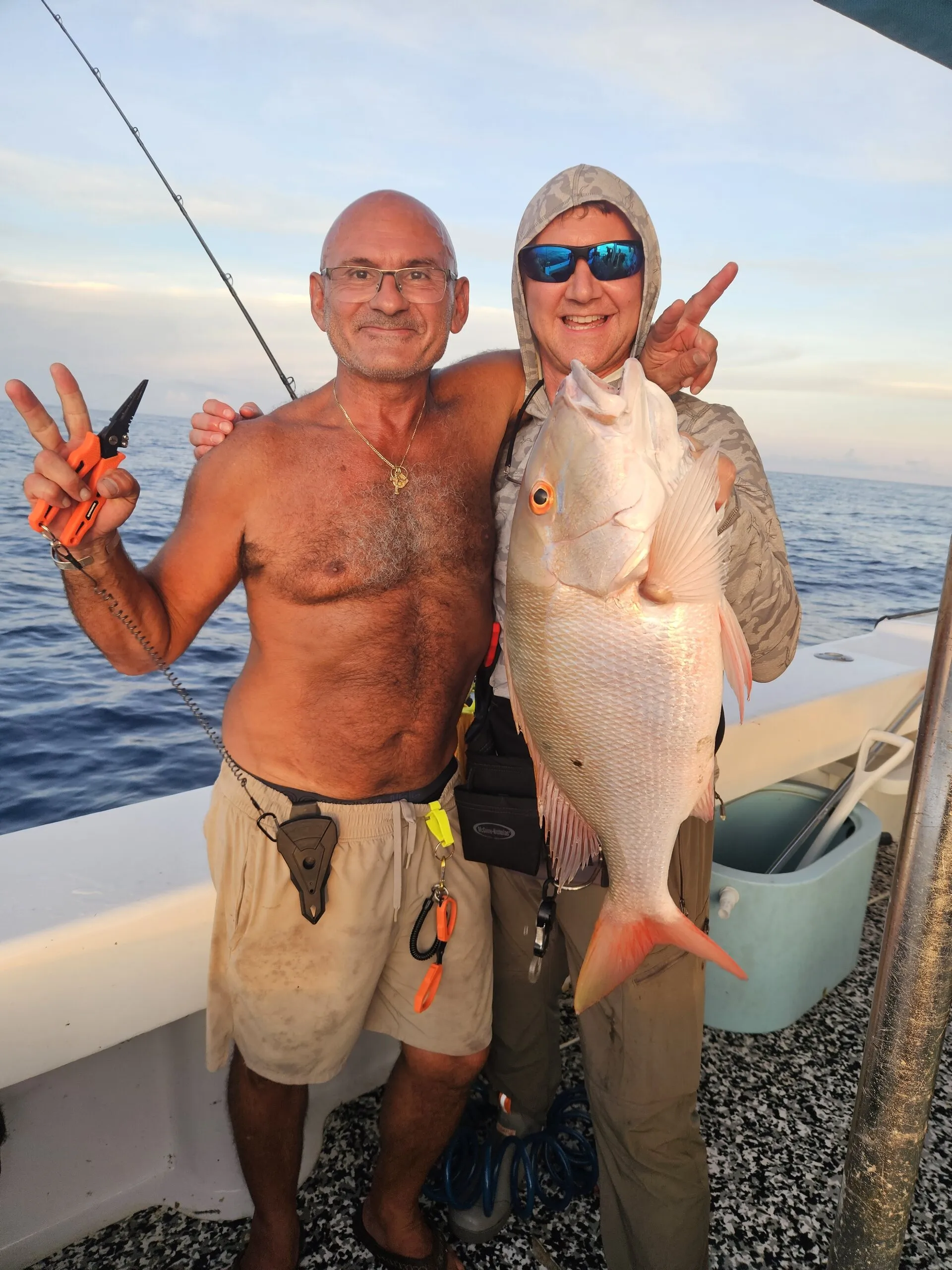 Two anglers with a snapper at sunset