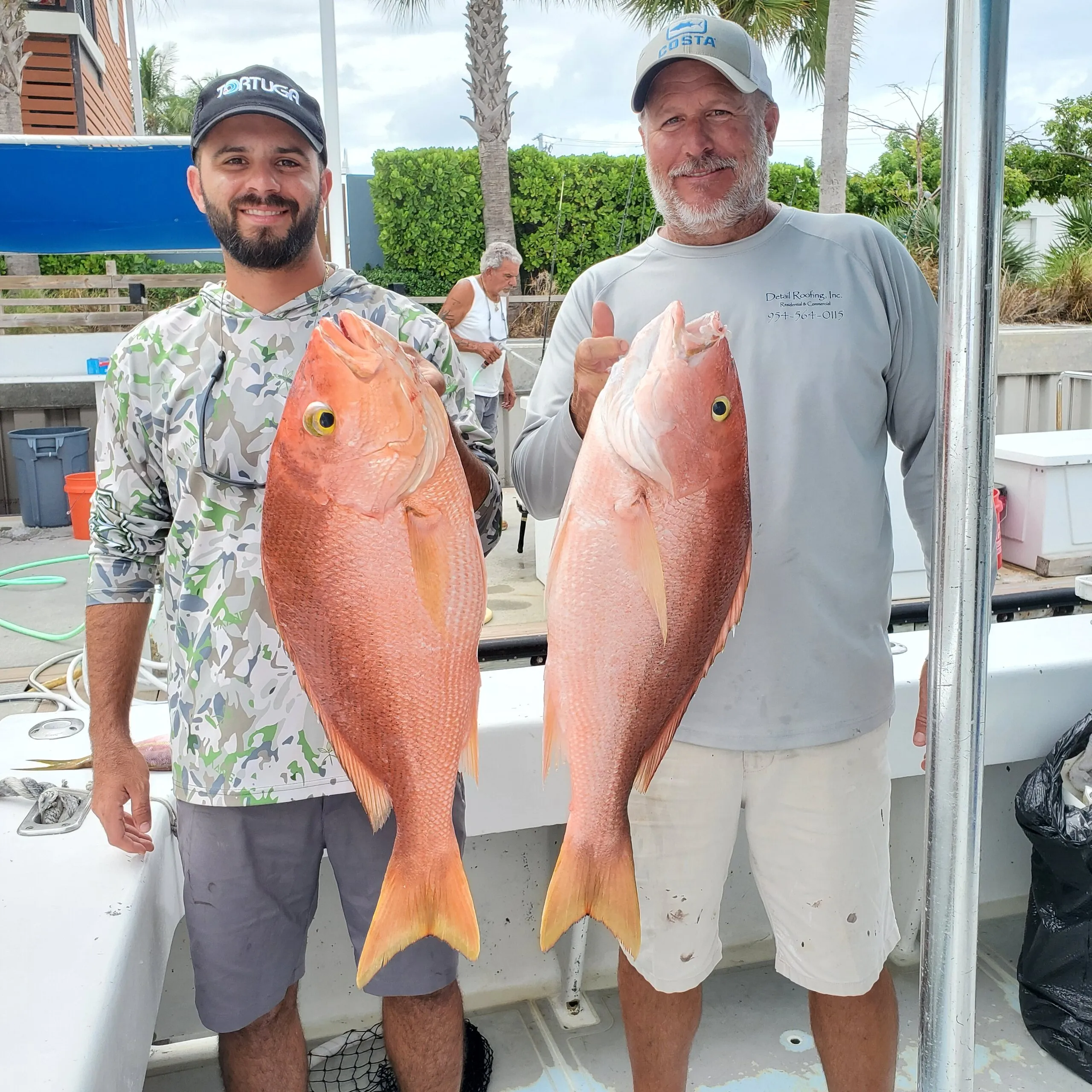 Two anglers with red snapper at the dock